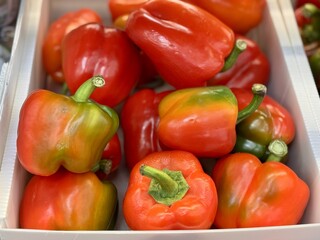 Pile of an washed fresh red sweet bell peppers on sale in vegetable stand display at supermarket show organic food, vegetarian food, healthy food. Close-up