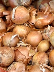 Pile of an yellow onion sale in vegetable stand display at supermarket show organic food, vegetarian food, healthy food