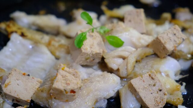 Cooking Indoors pan grilled seasoned Cod fillets and Tofu with spices and sun-dried tomatoes. On Stovetop, iron cast skillet, close up boiled oil, process deep fried.