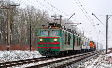 Obraz premium Old Soviet freight electric locomotive with a short train in winter in Kyiv Oblast of Ukraine