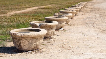 Naklejka premium Ancient stone water basins lined road, dry field background