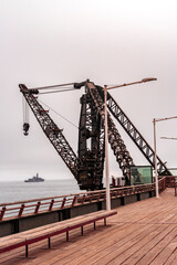 Fototapeta premium Tourists strolling and taking photos at the Vergara Pier in Viña del Mar on a cloudy winter day