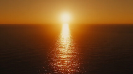 Obraz premium Golden sunset over calm ocean waters, reflecting a bright path of light across the rippled surface.