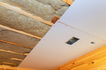 New drywall goes up on ceiling, over insulation during construction home
