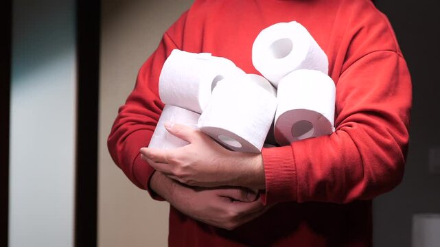 Man holding many toilet paper rolls at home. hoarding, panic buying, and fear of shortages