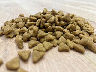 Pet food scattered on wooden surface, highlighting the nutritional shape and texture for canine or feline pets during meal preparation