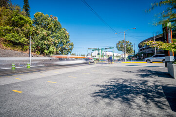 General view of a vehicular intersection with moving vehicles and people. Low speed photography with a fast motion effect.