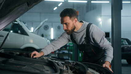 Professional mechanic man Caucasian male guy mechanical engineer specialist in uniform fixing car engine motor repairing electric automobile check auto maintenance in garage service industrial work