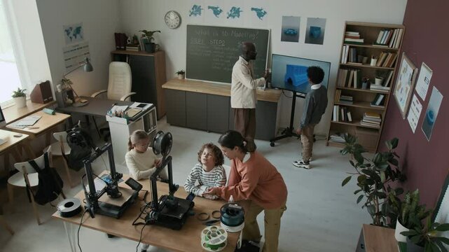 Extreme high angle shot of productive teamwork session of elementary school students during interactive 3D modelling class