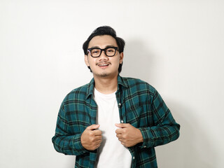 Handsome young Asian man smiling wearing a plaid shirt standing posing with a hand on his waist while looking at the camera confidently isolated on white background