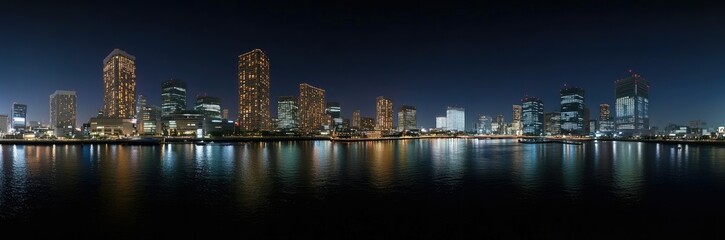 Naklejka premium Nighttime cityscape illuminated skyscrapers reflecting water