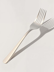 Silver fork resting on a neutral surface casting a delicate shadow during morning light