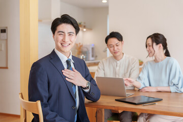 胸に手を当てる不動産営業マンと客夫婦