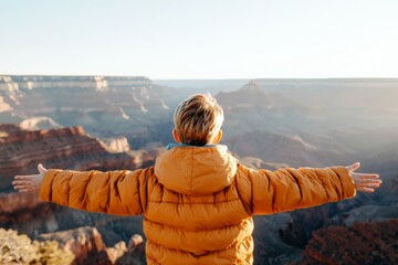 Young boy stands on a mountain top, wearing a yellow jacket, solo travel concept