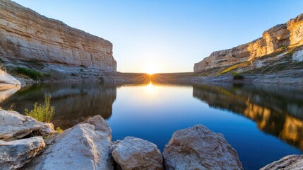 A stunning lake nestled between towering cliffs reflects the orange hues of the setting sun, creating a dreamlike space of tranquility