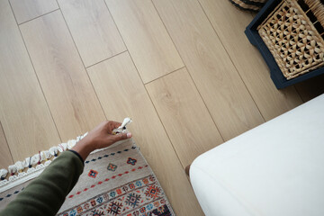 Person adjusting decorative rug in cozy interior setting