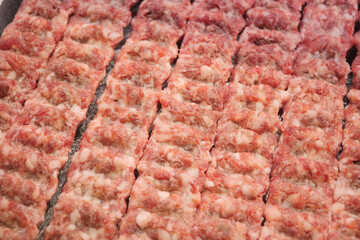 Freshly prepared minced meat arranged in neat rows for cooking