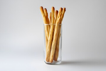 Crispy breadsticks in a tall glass jar on white background.