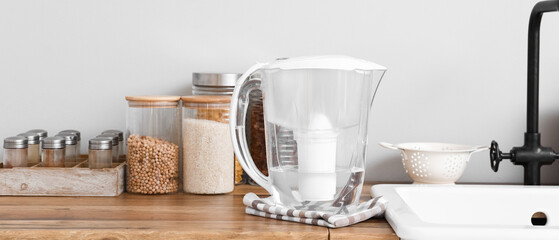 Water filter jug with napkin on kitchen counter near light wall