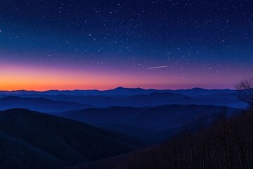 Starry night sky over a vast mountain range at sunrise, showcasing layers of blue and purple hues.