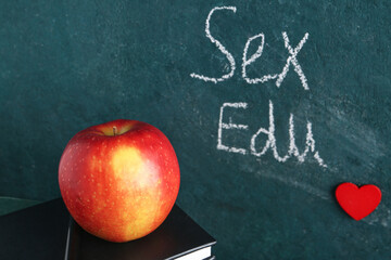 Apple, book and written text SEX EDU on dark background. Sex education
