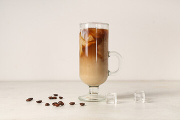 Glass cup of iced latte and coffee beans on white background