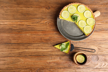 Plate and spatula with tasty lime tart on wooden background