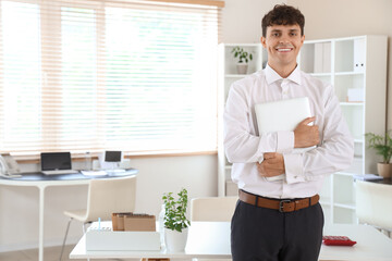 Fototapeta premium Male accountant with laptop near workplace in office