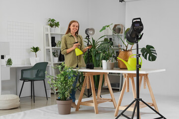 Female photographer watering plants in photo studio