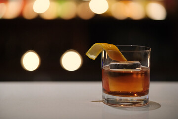glass of cocktail on bar counter, colorful bokeh at night