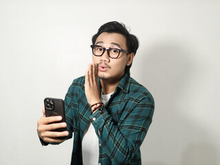 A man whispering something with happy expression while holding mobile phone isolated on white background