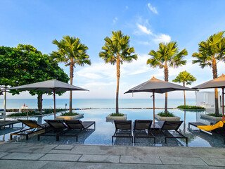 enjoy a serene moment by the pool in Thailand, surrounded by swaying palm trees and the tranquil ocean. Perfect for unwinding and soaking up the sun.