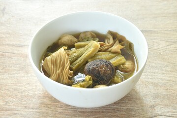 boiled pickled cabbage and bitter cucumber with tofu topping black mushroom in Chinese herb soup on bowl 