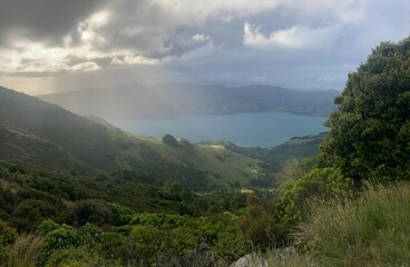Naklejka premium clouds over lake with green hills