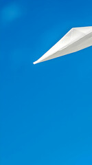 White paper airplane soaring in a clear blue sky, outdoor shot, ideal for concepts of freedom, dreams, and aspirations