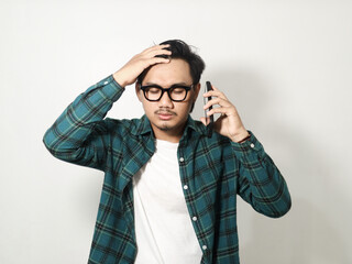 Adult Asian man showing stress expression while holding mobile phone isolated on white background