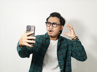 A man showing disappointed expression when looking to his mobile phone isolated on white background