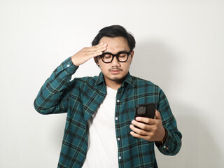 Adult Asian man showing stress expression while holding mobile phone isolated on white background