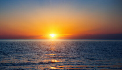 Fototapeta premium glowing sun setting over calm ocean radiating warmth and positive vibes