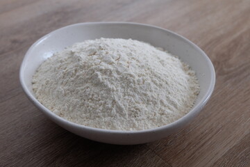 Flour in a white stone bowl with a wood background