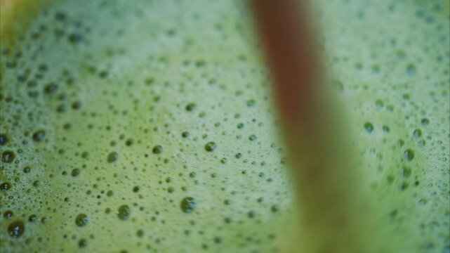 Close up of a woman mixing a matcha latte with a paper straw at a cafe