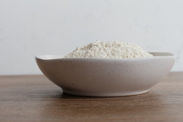 Flour in a white stone bowl with a white and wood background