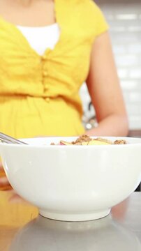 Pregnant woman eating cereal at home