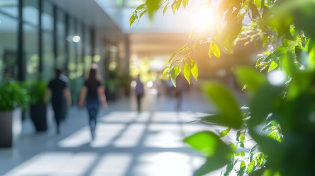 Modern office building with blurred business people walking in a bright environment featuring green trees and natural sunlight, showcasing an eco-friendly and sustainable corporate atmosphere focused 