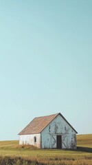 Obraz premium Rustic White Barn on Green Hill Under Clear Blue Sky in Daylight