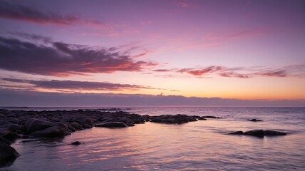 purple and orange sunset over the ocean with rocks in the foreground