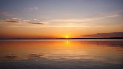 Fototapeta premium arafed view of a sunset over a calm lake with a boat in the water