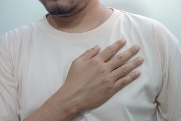 a person wearing a light shirt while placing a hand over their chest, symbolizing emotion,...