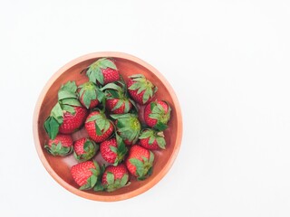 Strawberries in a wooden plate on a white background. Top of view. 