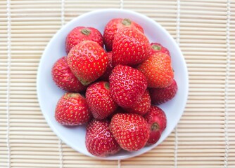 Close-up of strawberries in a small white plate. Top of view. 